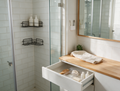 A bright tidy bathroom with a corner caddy, toothbrush holder and drawer trays