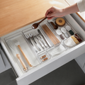 White drawer organizer trays hold utensils in a kitchen drawer